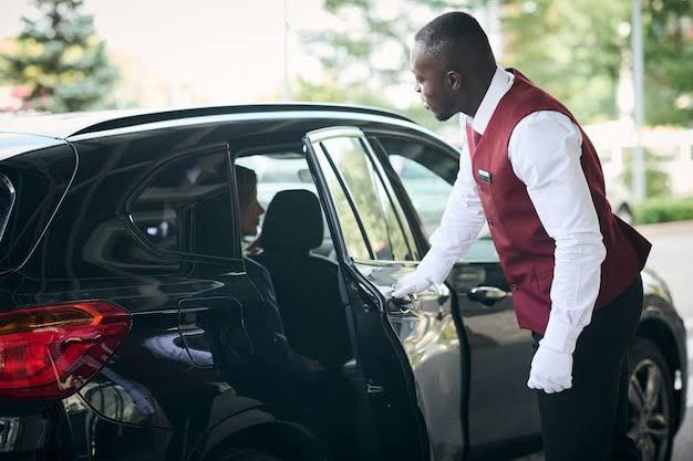 Professional chauffeur opening vehicle door for VIP client
